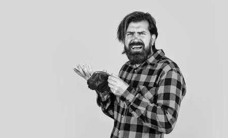 concept of finance and economy. unhappy man hold purse. poor man need some money. loan in crises. have money saving. ready to go shopping. bearded hipster in checkered shirt with walletの写真素材