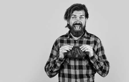 business and finance. difficult economic situation due to covid-19 pandemic. happy brutal hipster. bearded man hold wallets with money, shopping. brutal guy wear checkered shirt. male with purseの写真素材