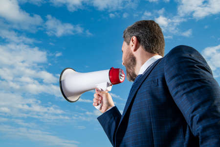 businessman shout loud in loudspeaker on sky backgroundの写真素材