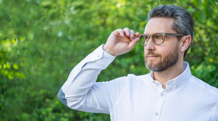 Portrait of professional man looking into distance in eyeglasses natural background, copy spaceの写真素材