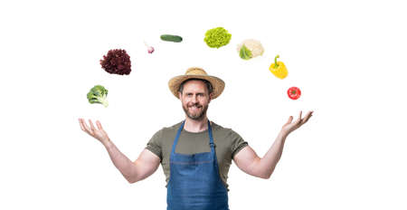 cheerful man in straw hat and apron with colorful vegetables isolated on white background
