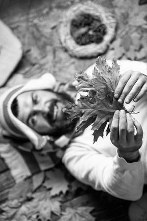 Follow me. autumn male fashion. Carefree and happy. man hold maple leaf. canada. hipster relax on autumn background. handsome in autumn style. human in nature. Staying cheerful any seasonの写真素材