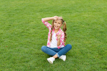 happy teen kid sit on green grass outdoorの写真素材