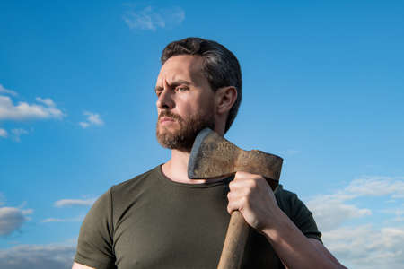 bearded man with axe. caucasian man hold ax. brutal man on sky background