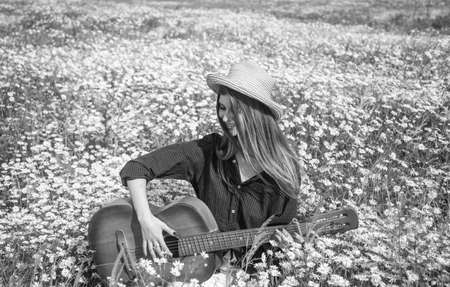 Spending nice time. romantic mood. beauty of spring nature. happy girl with guitar in chamomile flowers. summer vacation and holiday. pretty woman wear hat in chamomile field. singer in meadowの写真素材