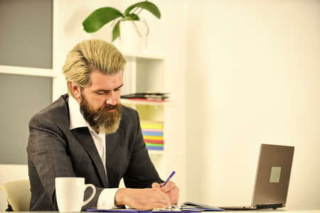 Full concentration at work. Elegant businessman analyzing data in smartphone. Quarantine agile business. lawyer use notebook for work. bearded man sit at desk in office. confident brutal businessmanの写真素材