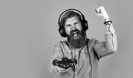 bearded brutal man with moustache wear headphones play computer games with console, gaming