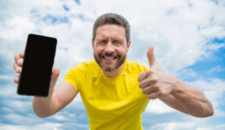 glad man presenting screen of smartphone with copy space