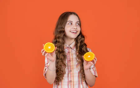 positive teen child hold citric fruit on orange backgroundの写真素材