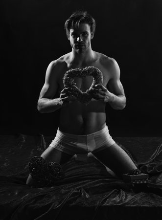 sexy macho guy with muscular body wear pants hold heart shape decor for valentines day, potencyの写真素材