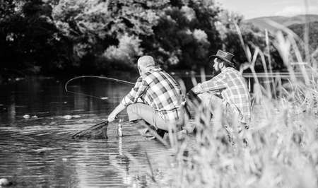 Two male friends fishing together. big game fishing. relax on nature. happy fishermen friendship. retired father and mature bearded son. fly fish hobby of men. retirement fishery. We have caught itの写真素材