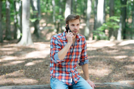 young handsome man in checkered shirt speak on phone outdoorの写真素材