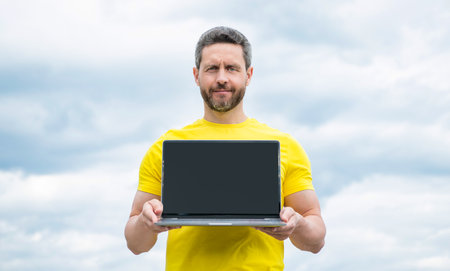 man presenting pc on sky background. copy spaceの写真素材