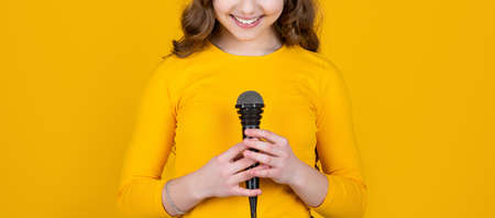 cropped view of teen child with microphone on yellow backgroundの写真素材