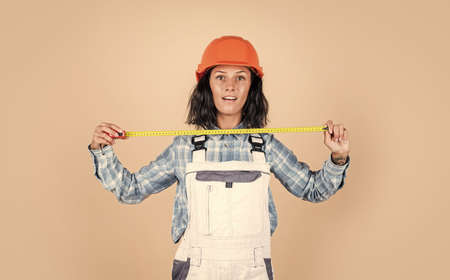 safety uniform. equipment for repairing. mechanic girl in protective hardhat. building and construction. professional manual worker. technician working using tape measure toolの写真素材