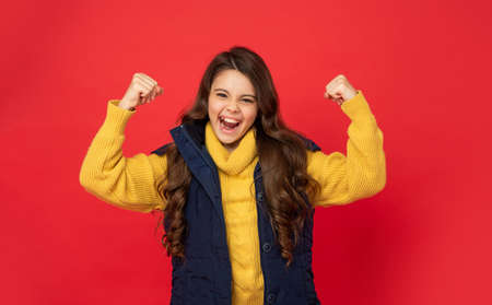 happy successful kid with curly hair in sweater. female fashion model. teen girl in down vest.の写真素材