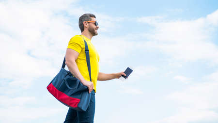 Man traveler traveling on vacation with travel bag and document sky background, copy space