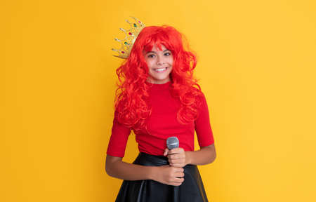 child smile in crown with microphone on yellow backgroundの写真素材