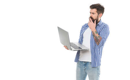 Something wrong with computer. Professional computer repairman or tech worker. Bearded man looking at his computer. Surprised hipster holding laptop computerの写真素材