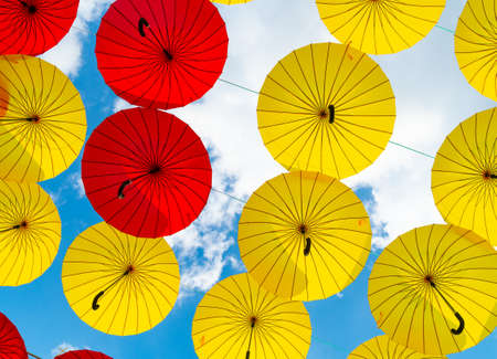 Bright color umbrellas hanging bottom-up sky backgroundの写真素材