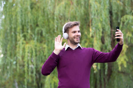 young handsome man listen music and making selfie on phone outdoorの写真素材