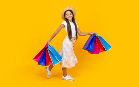 smiling teen girl with shopping bags on yellow background. full lengthの写真素材