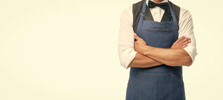 Confident man crop view in bow and apron keeping arms crossed isolated on white copy space, baristaの写真素材