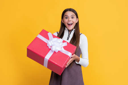 happy amazed child with present box on yellow backgroundの写真素材
