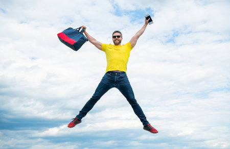 Active man jumping with travel bag midair sky background, vacationの写真素材