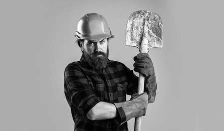 brutal man builder in uniform and helmet with shovel, architecture