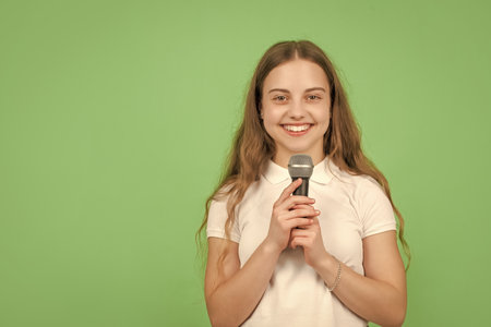 happy child singing in microphone on green background with copy space, musicの写真素材