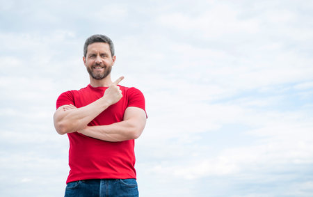 happy man in red shirt point finger on on sky background