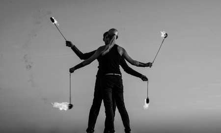 couple in love dance while spinning burning poi blue sky outdoors, fire showの写真素材