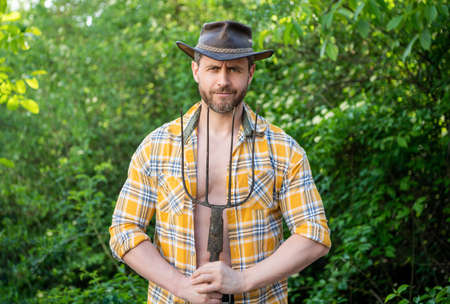 Peasant holding pitchfork outdoors. Unshaven guy wearing peasant hat and plaid shirt. Peasant manの写真素材