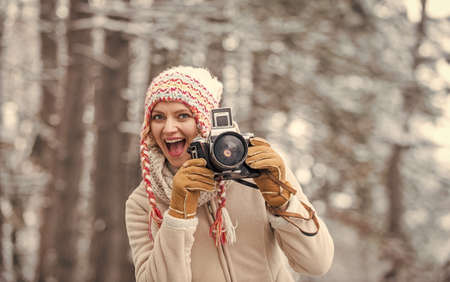 Girl with vintage camera in snowy nature. Traveling concept. Capturing winter. Take stunning winter...