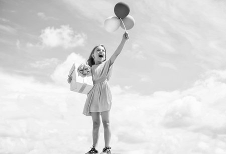 freedom. beautiful teen girl with present box. kid fashion style. female natural beauty. happy childhood. cute child on sky backdrop with balloons. spring season weather. summer holiday and vacationの写真素材
