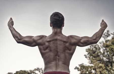 Athlete with bare torso on grey skyの写真素材
