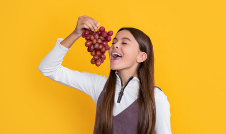amazed surprised child hold healthy grapes fruit on yellow backgroundの写真素材
