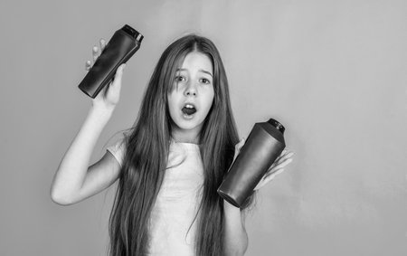 time for grooming. strong and resilient. amazed girl ready to condition hair with straightener. girl cleaning hair with shampoo. kid presenting shower gel. body care cosmetic bath shower. skin lotionの写真素材