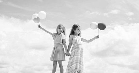 Cute and stylish. kid fashion. cheerful family day. fashion and beauty. sisterhood or friendship concept. smiling children with party balloons. childhood happiness. pretty teenage girls sistersの写真素材