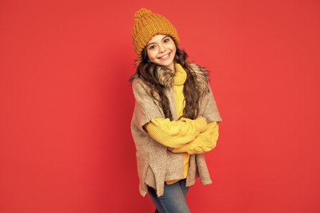 happy teen girl in knitted winter hat on red background, fashionの写真素材