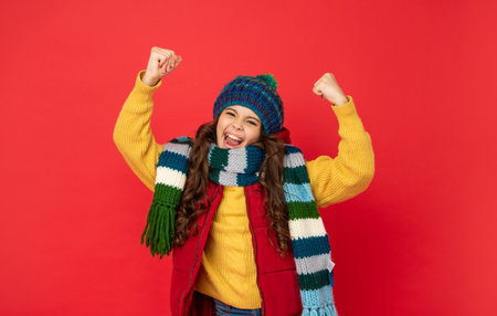 successful child in knitted winter hat and scarf on red background, successの写真素材