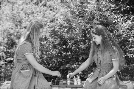 two teen girls play chess in retro dress outdoor, strategyの写真素材