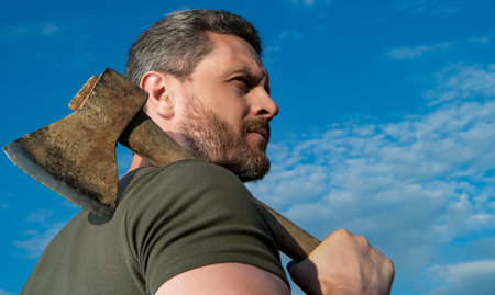 man with axe. brutally man hold ax. brutal man on sky backgroundの写真素材
