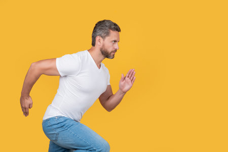 Active man running. Guy runner running on studio yellow background. Dynamic running, copy space