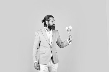 mature bearded male guy looking elegant with spring tulips, flowerの写真素材