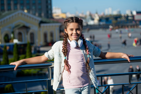 Happy girl leaning against railing. Teenage girl with pigtails smiling outdoors. Adolescent girlの写真素材