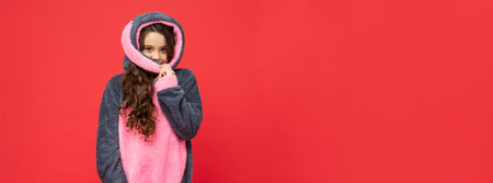 smiling teen girl in soft night suit on red background with copy space, homeの写真素材