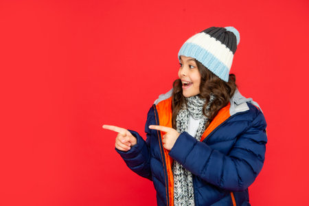 express positive emotion. winter fashion. point finger on copy space. amazed kidの写真素材