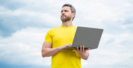 freelancer working online on laptop on sky backgroundの写真素材